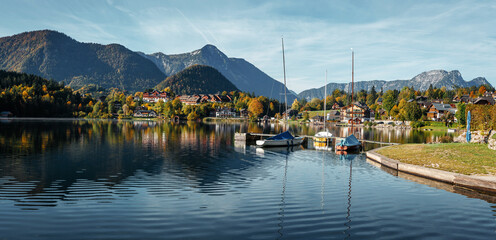 Obraz premium Amazing nature scenery. View on Alpine lake Grundlsee with Typical fishing huts in sunny day. Grundlsee is a one most popular travel locations in Europe. Wonderful Summer landscape.
