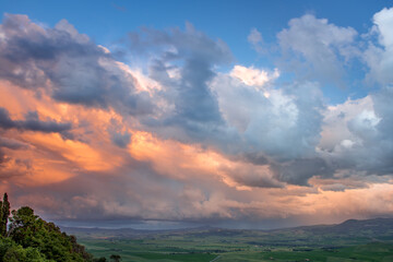 Sunset lighting up clouds over farmland near Pienza in Tuscany