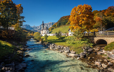 Beautiful nature landscape. Incredible autumn scenery. View on Alpine highlands with rock mountains, colorful trees and Small church on the river bank.view on famous Parish Church of St. Sebastian