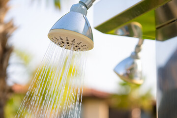 Outdoor refreshing shower head  spraying water to take shower before swimming in the pool or the...