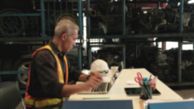 Blur Focus VDO: Caucasian male engineer concentrate working on desk. Checking order and stock of car engines, and machinery in automotive industry with laptop in a spare parts factory warehouse.