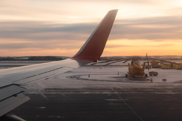 Fototapeta na wymiar Yekaterinburg. Russia. 12/20/2020. The view from the airplane window of the runway and part of the silvery-red wing during takeoff at dawn. Ural Airlines. Aeroflot