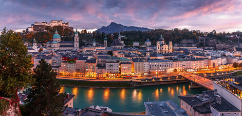 Fototapeta premium Colorful evening cityscape. Stunning view on historic city of Salzburg with famous Hohensalzburg Fortress. Wonderful autumn landscape with picturesque sky. Softlight effect. Salzburger Land, Austria