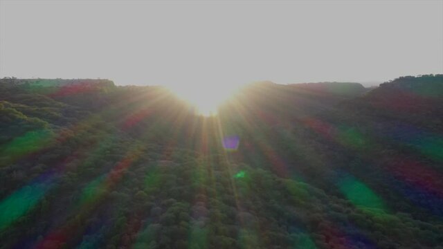 A clip of sunset over a hill with full sunray colors. The rainbow colored sunrays are displayed in slow motion.