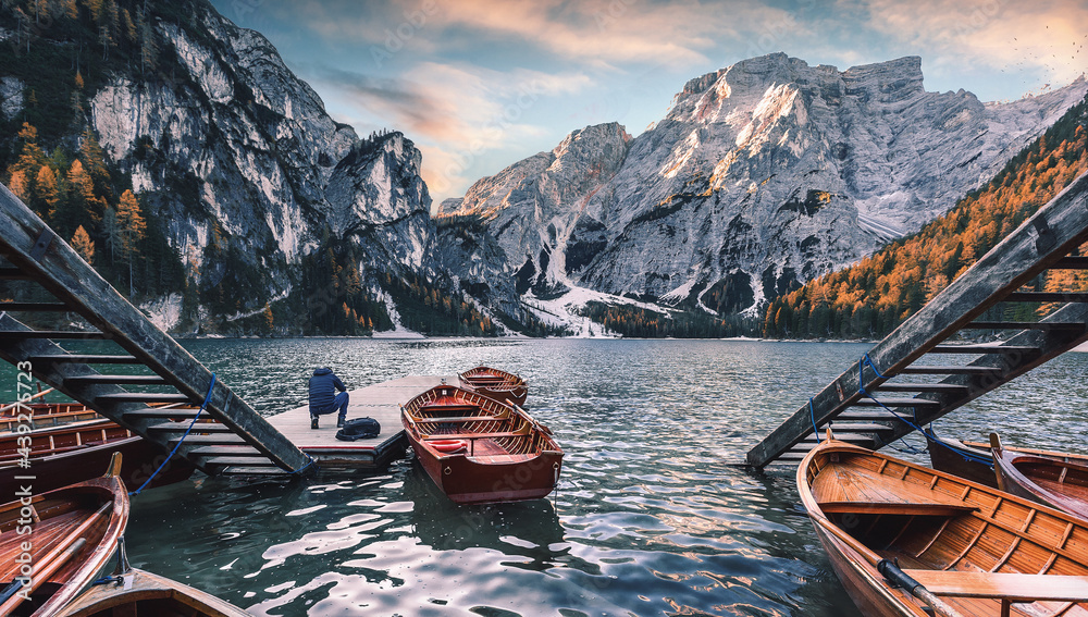 Fototapete Autumn nature landscape. Spectacular famous place with typical wooden boats. View on Braies alpine lake during sunrise. Lago di Braies. Dolomites Alps. Italy. Popular Iconic location for photographers