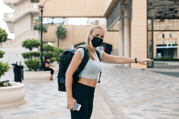 A young tourist girl in a face mask with a backpack is traveling during a vacation. Travel and tourism industry during the pandemic