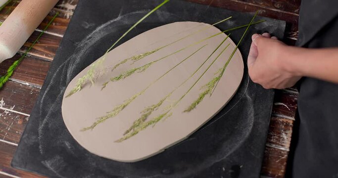 High angle view of female hands removing leaf out of clay plate. Close-up, slow motion