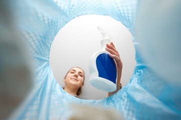 recycling, waste sorting and sustainability concept - woman throwing plastic bottle of detergent...