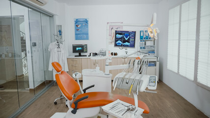 Empty stomatology orthodontist bright office room with nobody in it equipped with professional medical dentistry teeth instruments prepared for dental health surgery. Cabinet ready for tooth surgery