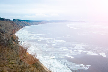 View of the Volga River from a high cliff in the spring afternoon. Melting chunks of ice float through the water. Spring melting ice.