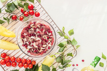 Food composition with beef, new crop seasonal vegetables on a grill, bottle of white wine and birch twigs. Cooking meat with farm vegetables in the open air. The concept of a picnic and healthy food