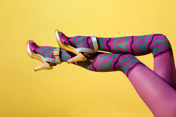 Sexy shapely female legs in multicoloured purple collant