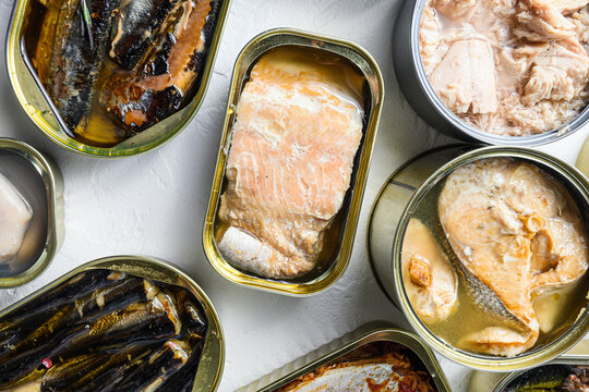 Set aluminium and tin cans with  Saury, mackerel, sprats, sardines, pilchard, squid, tuna over white textured background close up