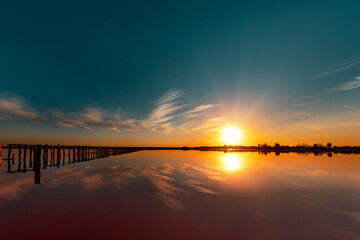 Obraz premium pink lake and sandy beach with a sea bay under a blue sky with clouds