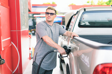 White caucasian car owner filling high energy power fuel in auto car tank and looking at fuel...