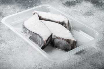Frozen Greenland halibut steaks vacuum pack, on gray stone table background, with copy space for...