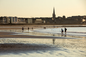  Romantic walk of people before sunset on the picturesque beach of Saint Malo. Brittany, France