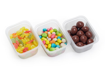 Candies of three variety in small plastic containers, close-up