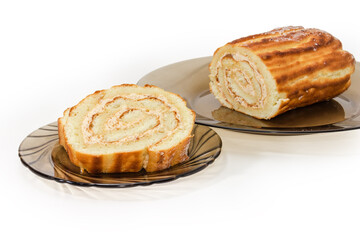 Partly sliced Swiss roll on glass dishes on white background