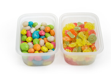 Candies of two variety in small plastic containers, close-up