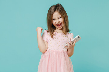 Little fun cute kid girl 5-6 years old wears pink dress hold in hand using mobile cell phone isolated on pastel blue color background child studio portrait. Mother's Day love family lifestyle concept.