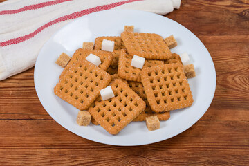 Flat square sugar shortbread cookies and sugar cubes on dish