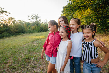 Fototapeta premium A group of cheerful girls are smiling and playing in the Park during sunset. Children's summer camp