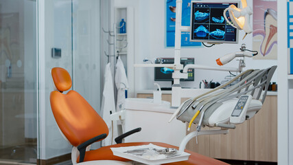 Revealing shot of stomatologist chair with nobody in, x ray images on display. Medical clinic orthodontic room, ready for treatment, modern dentist office for oral care