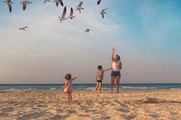 Mother with a little son and daughter are feeding seagulls on the shores of the Atlantic Ocean in Cuba, the island of Cayo Coco.