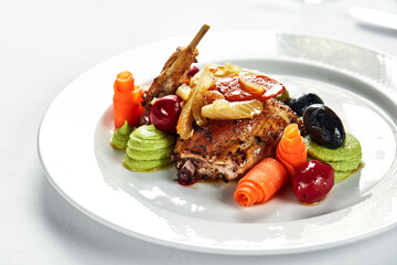 Stewed quails on a light plate, with vegetables and olives, light background, quail cooked by stewing, serving catering