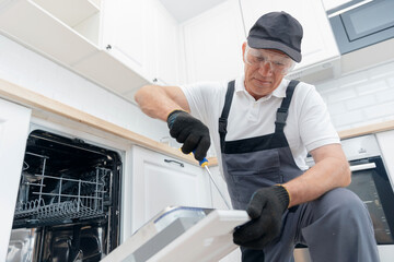 Service for repair and installation of dishwasher, male worker with tool in uniform