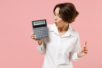 Young surprised successful employee business secretary woman corporate lawyer in classic formal white shirt work in office hold in hands calculator isolated on pastel pink background studio portrait - obrazy, fototapety, plakaty