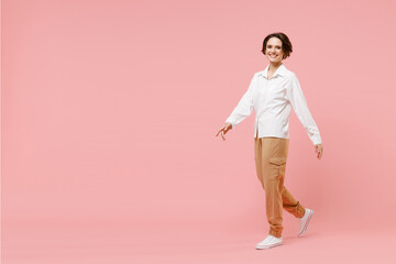 Fototapeta na wymiar Full length side view young smiling happy successful employee business woman corporate lawyer in classic formal white shirt work in office walking isolated on pastel pink background studio portrait