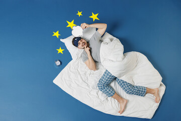Full length top view young man in pajamas jam sleep mask rest home lie cover under blanket blank Say cloud speech bubble content isolated on dark blue sky background Good mood night bedtime concept