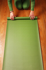 A woman rolls out a green mat before a yoga class