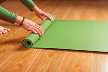 A woman collects a green mat after a yoga class