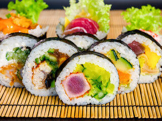 set of sushi rolls on bamboo mat on black background.