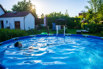 A teenager relaxes in the swimming pool at sunset