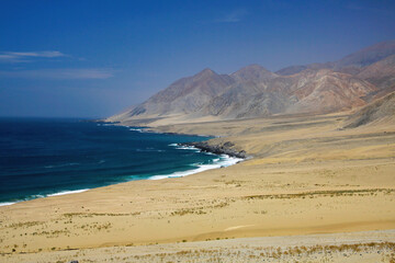 Rough harsh coastal scenery: View on uninhabited barren bay with empty sand beach at endless pacific coast with dry arid mountains - Pan de Azucar, Chile