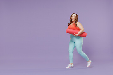Fototapeta premium Full length side view happy young chubby overweight plus size big fat woman 20s wear red top warm up train hold yoga mat walk isolated on purple background gym home. Workout motivation sport concept