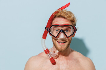 Close up handsome young smiling fun blond man 20s wear swimsuit diving snorkeling mask relax near hotel pool look camera isolated on pastel blue background. Summer vacation sea rest sun tan concept