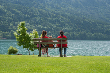 persone sedute su una banchina ammirano il lago