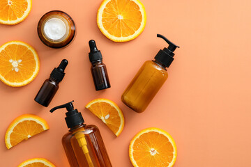 Amber glass bottles with Vitamin C cosmetics and sliced orange top view. Natural beauty products design.