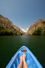Kayaking through river in Matka canyon, Macedonia. Woman legs in the blue kayak - obrazy, fototapety, plakaty