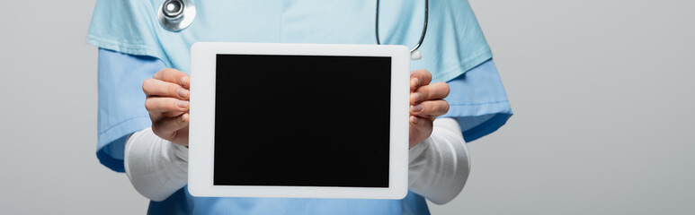 cropped view of muslim doctor showing digital tablet with blank screen isolated on grey, banner