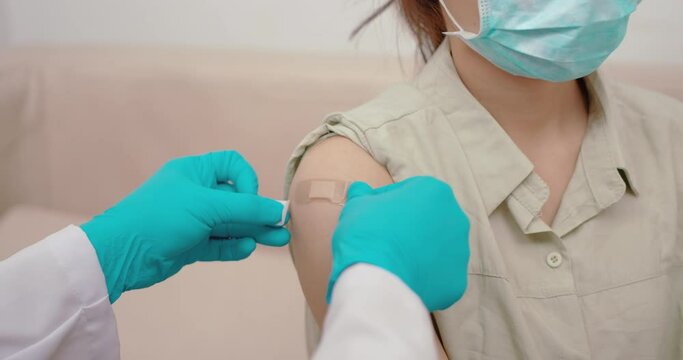 Adhesive bandage on arm after injection vaccine or medicine, Asian woman sitting in a clinic wearing a mask is injected with a vaccine to immunostimulating medication during a coronavirus outbreak.