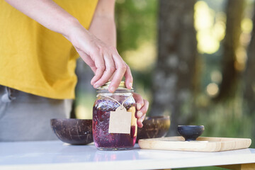 Woman packaging a mixture of macerated essential oils for natural cosmetics in the forest.