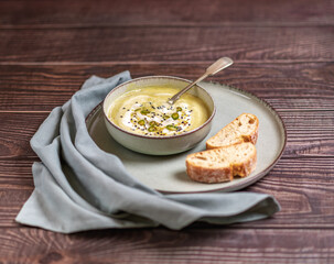Food photography of a vegan pumpkin cream soup and bread with selective focus. Vegetables recipe. An autumn puree of seasonal products on a wooden table.
