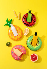 Summer vacation cosmetics. Sun protection lotion, sunscreen, moisturizer. Summer skin care concept. Mockup of sunscreen products in bottles on bright yellow background with fruits