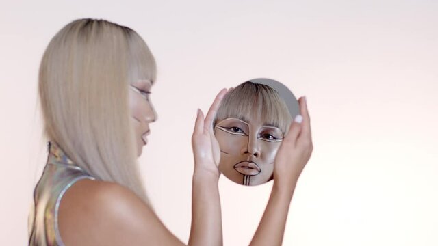 Woman with futuristic make up looking into round mirror